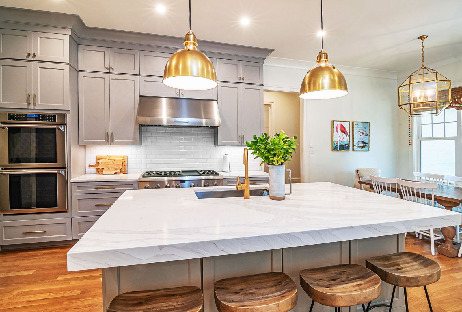 Kitchen with a white marble-look island and brass pendants