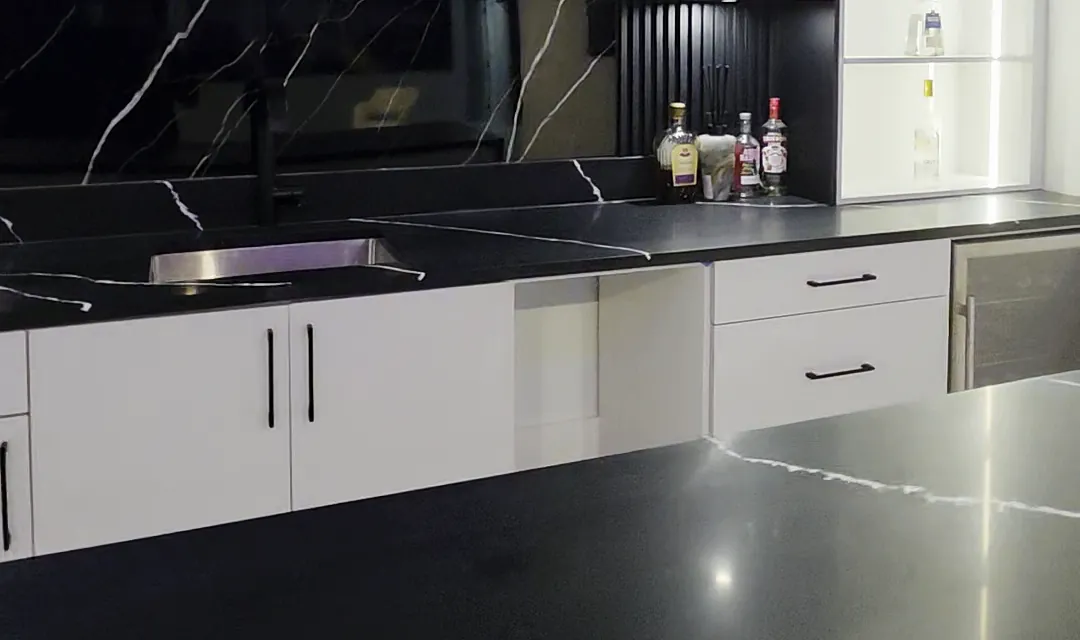 Back bar counter in black stone with an undermount sink and a stone backsplash